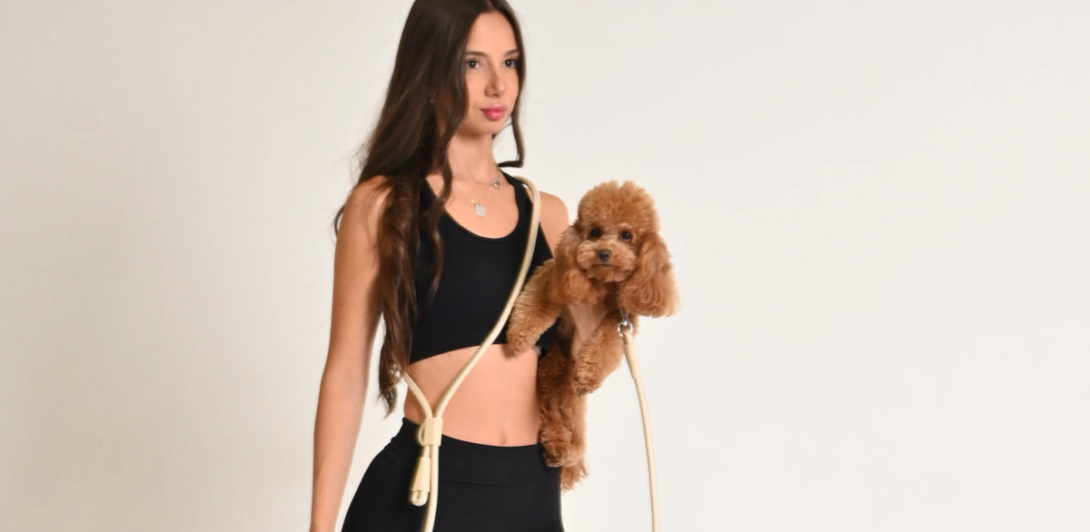 Stylish girl in yoga set holding cute dog and hands free dog leash